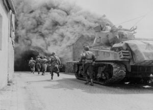 Soldiers of the 55th Armored Infantry Battalion and tank of the 22nd Tank Battalion, move through smoke filled street. 