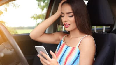 Upset young woman with cell phone in car