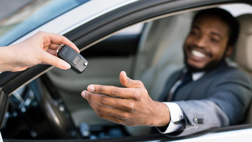Professional salesperson giving keys to new car owner.