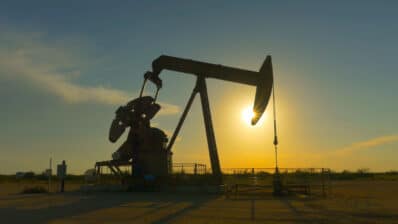 Industrial jack pump platform pumping crude oil over sunset sun